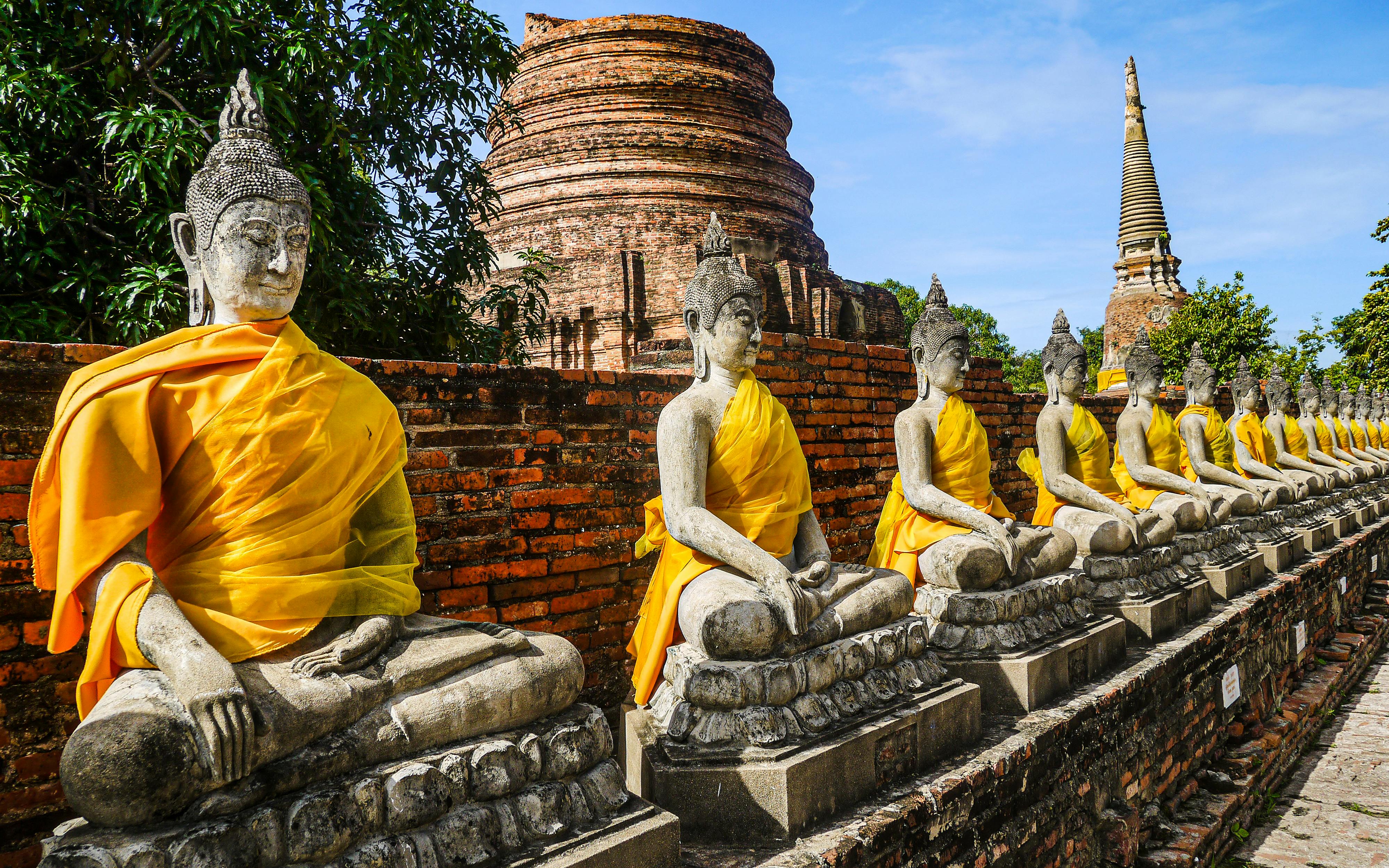 Rows of seated Buddha statues in saffron robes lining the grounds of Wat Yai Chai Mongkhon in Ayutthaya
