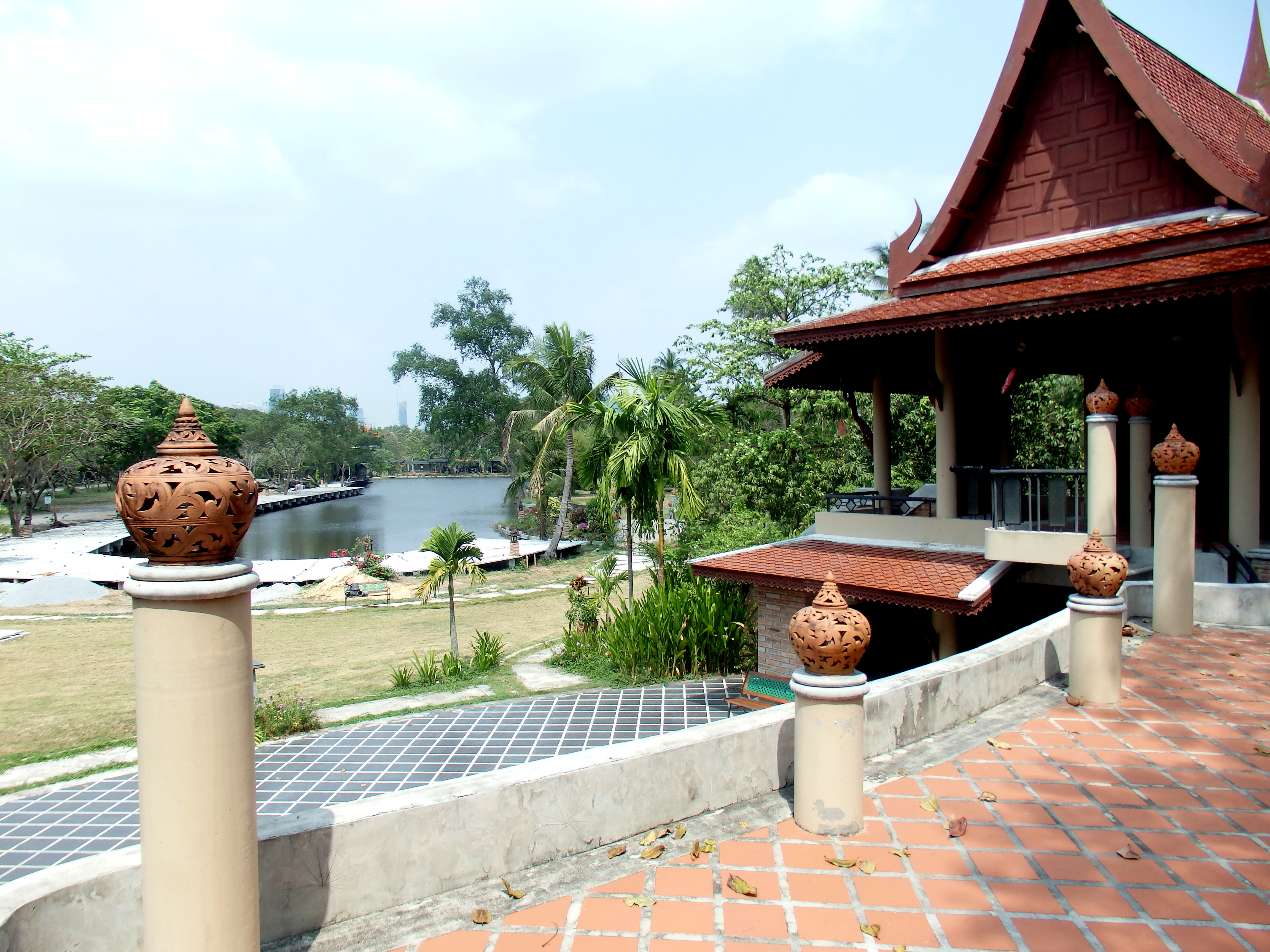 Thai pavilion by a lake in Bang Kachao, with the Bangkok skyline behind