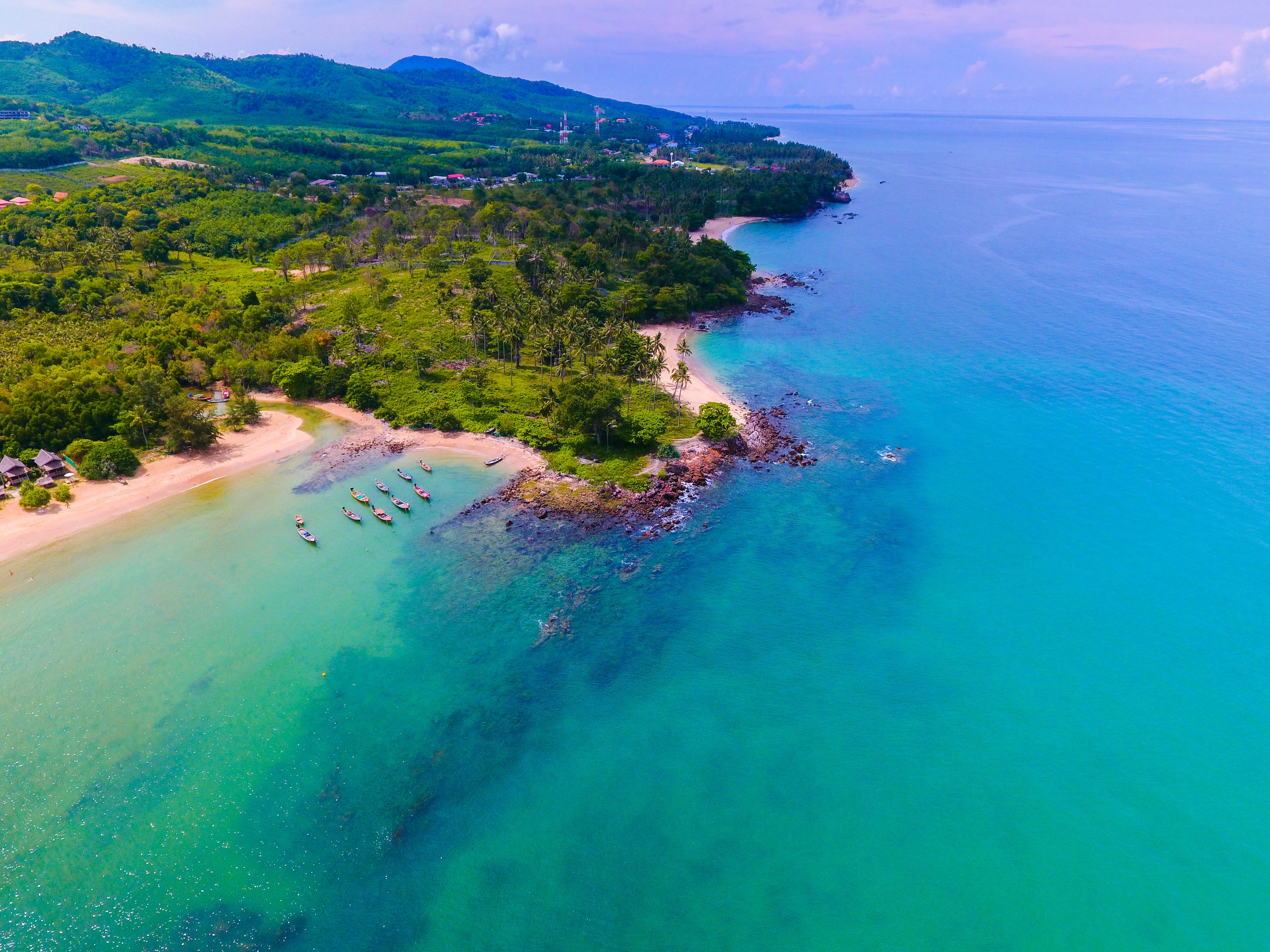 Longtail boats moored off a quiet Koh Lanta beach seen from above